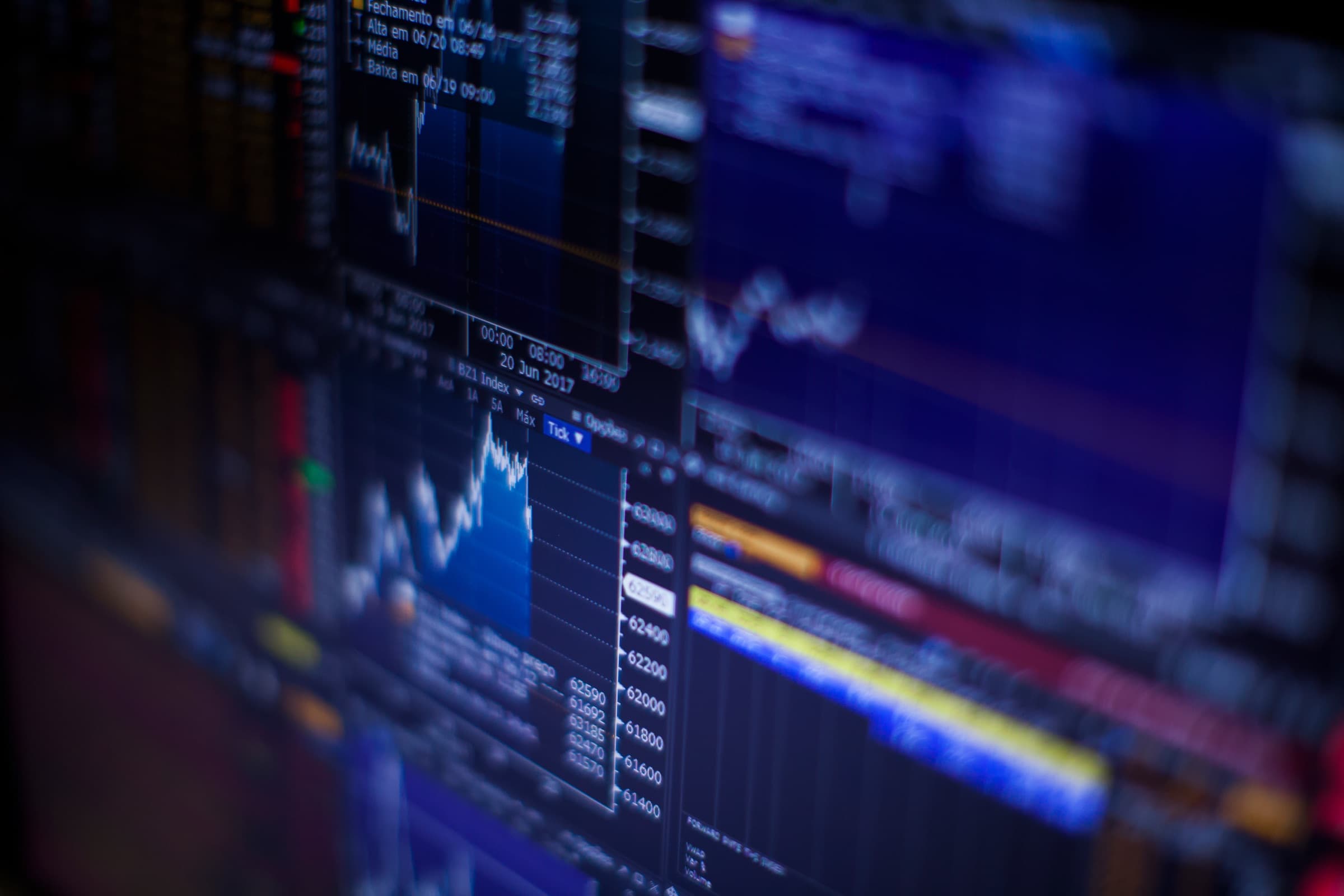 A trading terminal at an angle, its screens filled with price charts and order books.