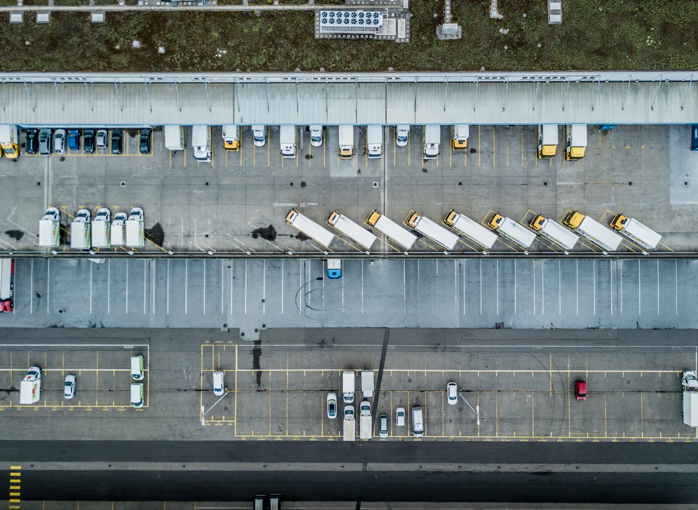 An overhead view of a distribution centre yard, trailers backed onto the loading bays.